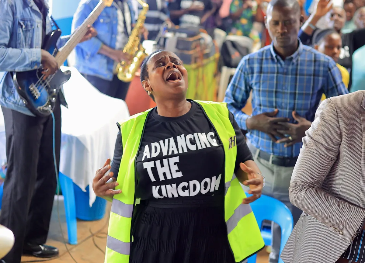 A steward in a high visibility vest singing in worship