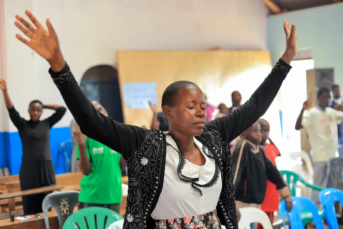 A woman worshipping with both arms stretched out