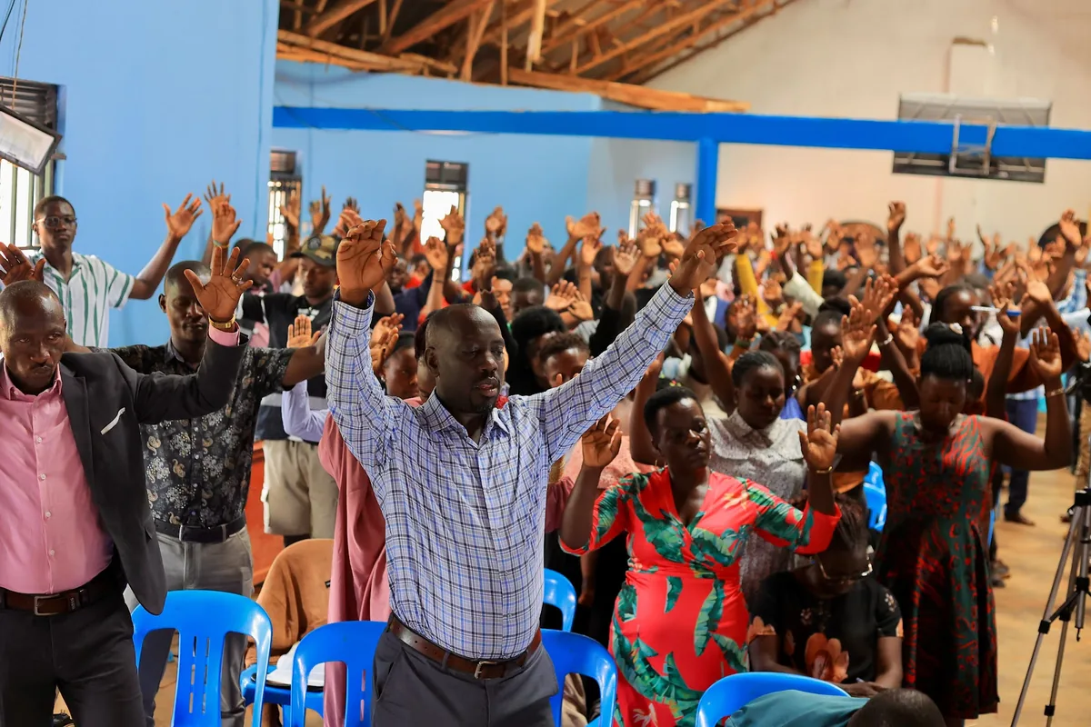 The congregation standing with hands raised in prayer
