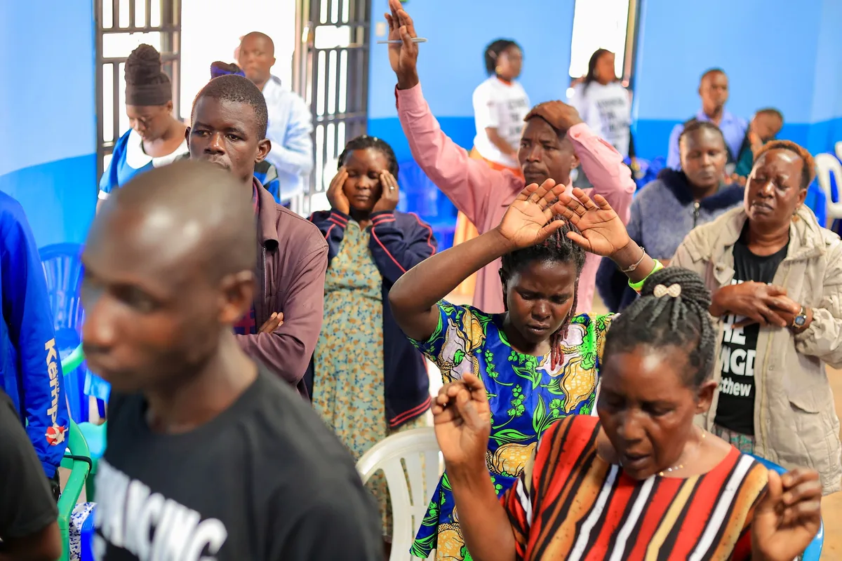 A man praying with his eyes closed during a gathering