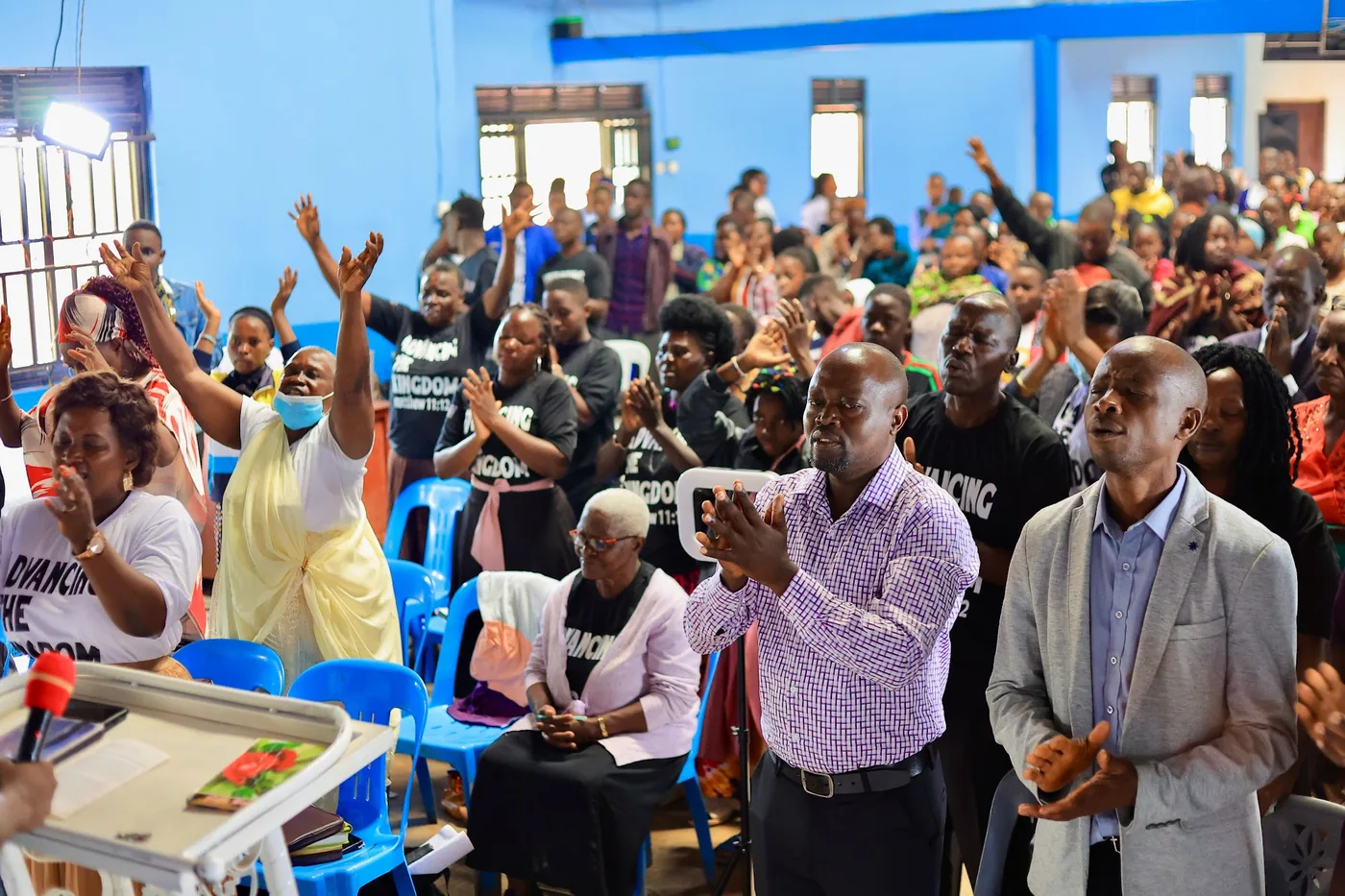 A packed hall of people standing in worship