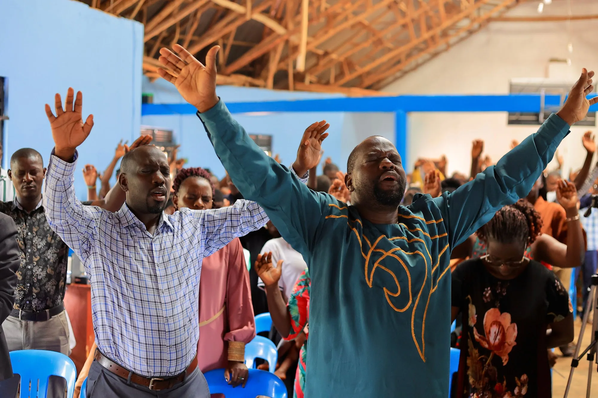 A man standing with both arms raised in worship