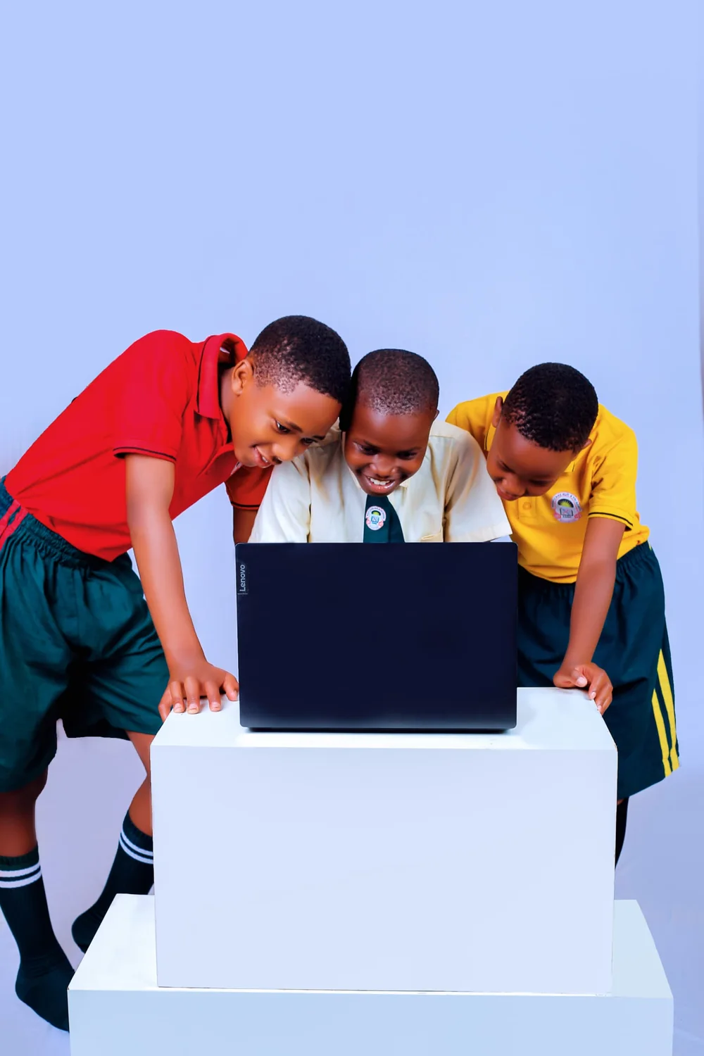 Three pupils in school uniform working together at a laptop