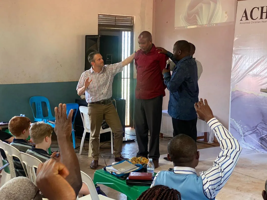 A visiting teacher praying with members at the front